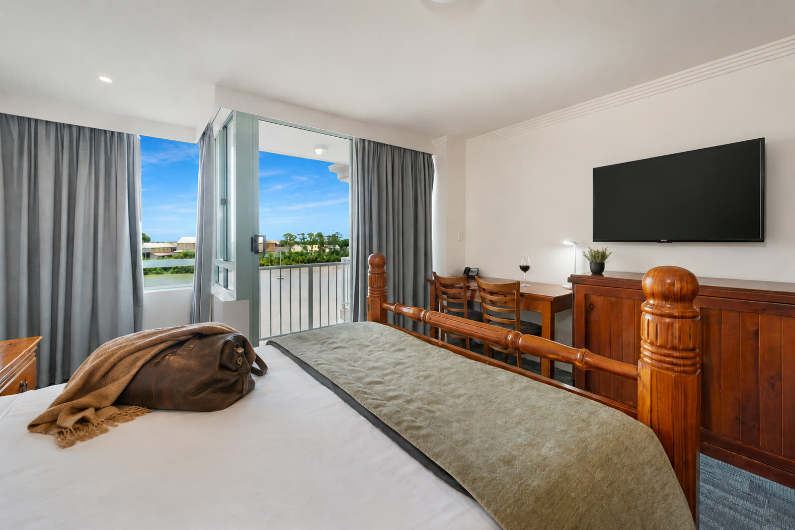 A guest room at Burnett Riverside Hotel with the balcony door open to the river