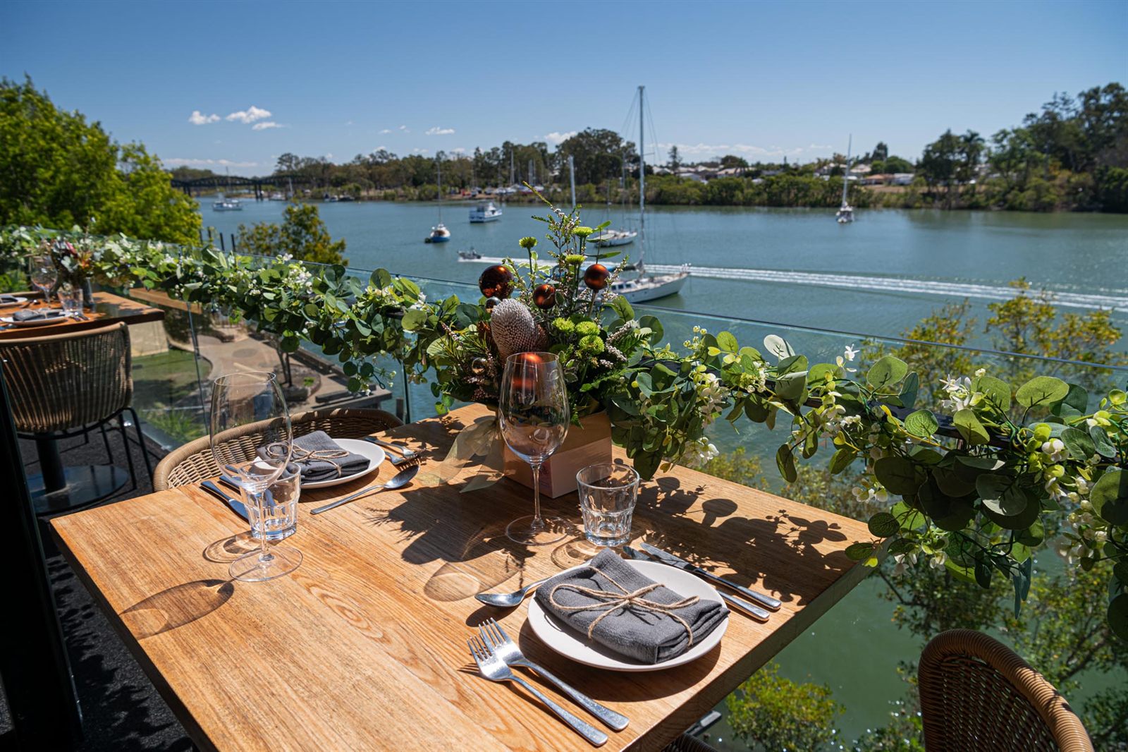 A table dressed for Christmas on the deck, with a native garland and the Burnett River behind