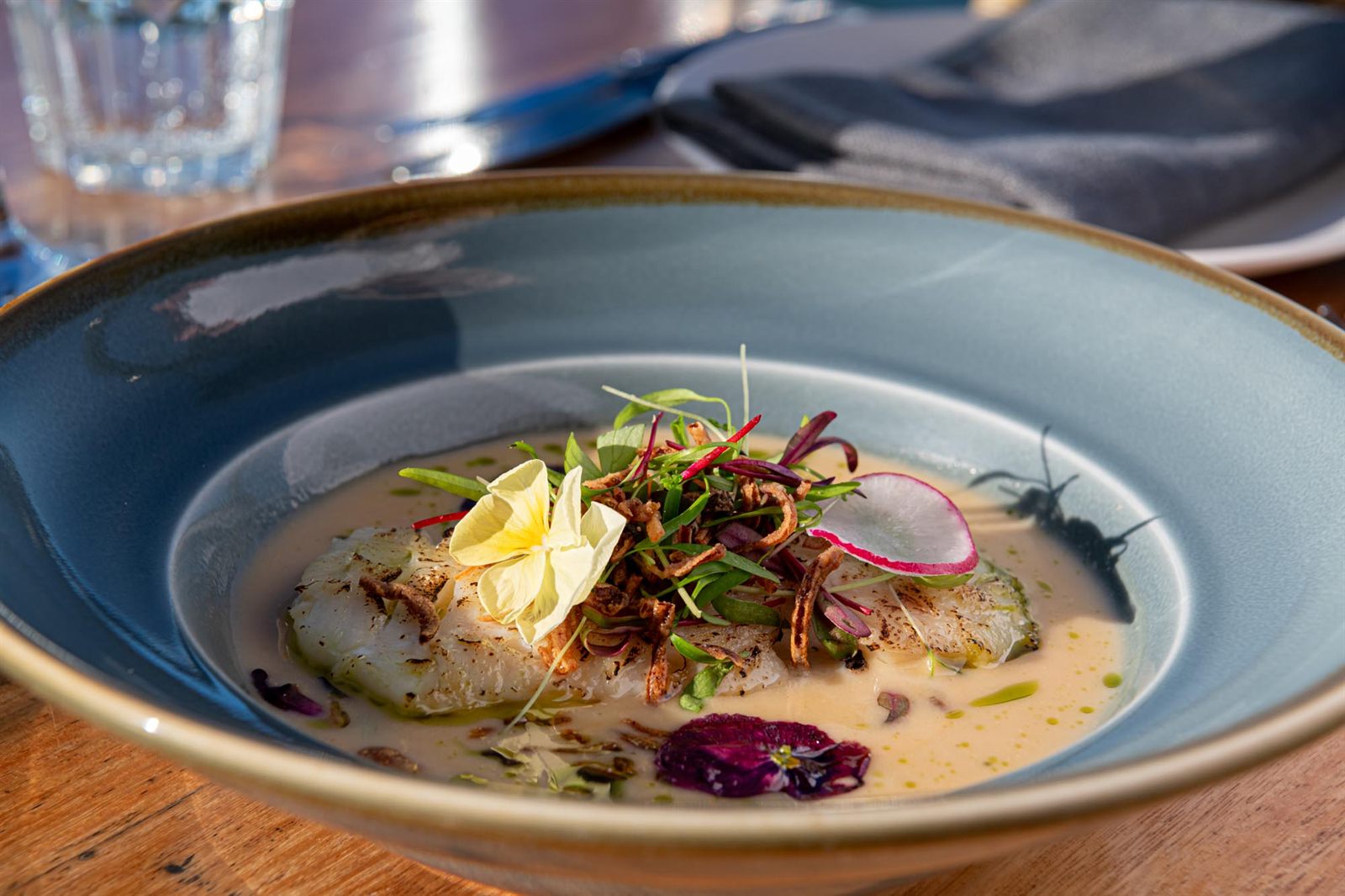 A plated H2O dish in a blue stoneware bowl, served on the riverside deck